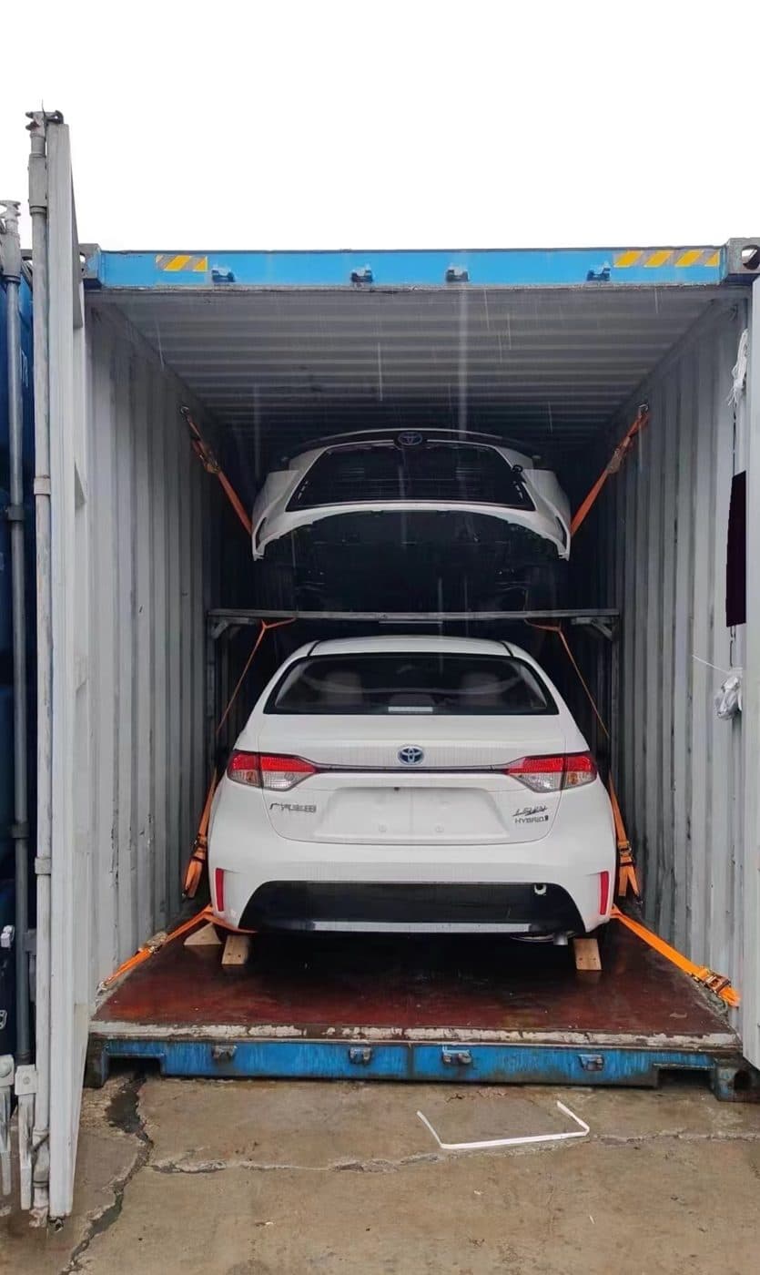Two cars loaded on a double-deck rack inside a container